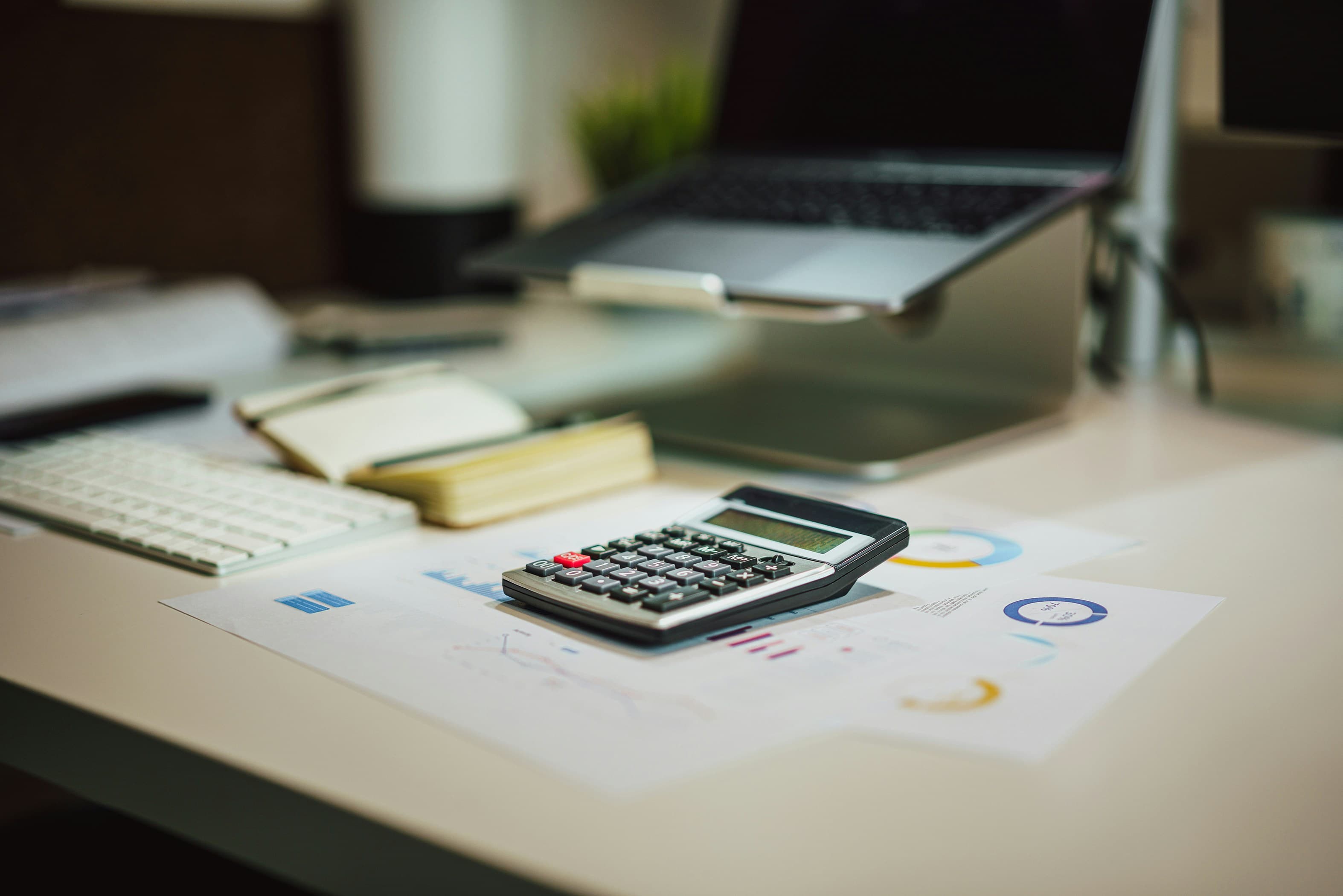 Una calculadora encima de una mesa junto a un ordenador portátil