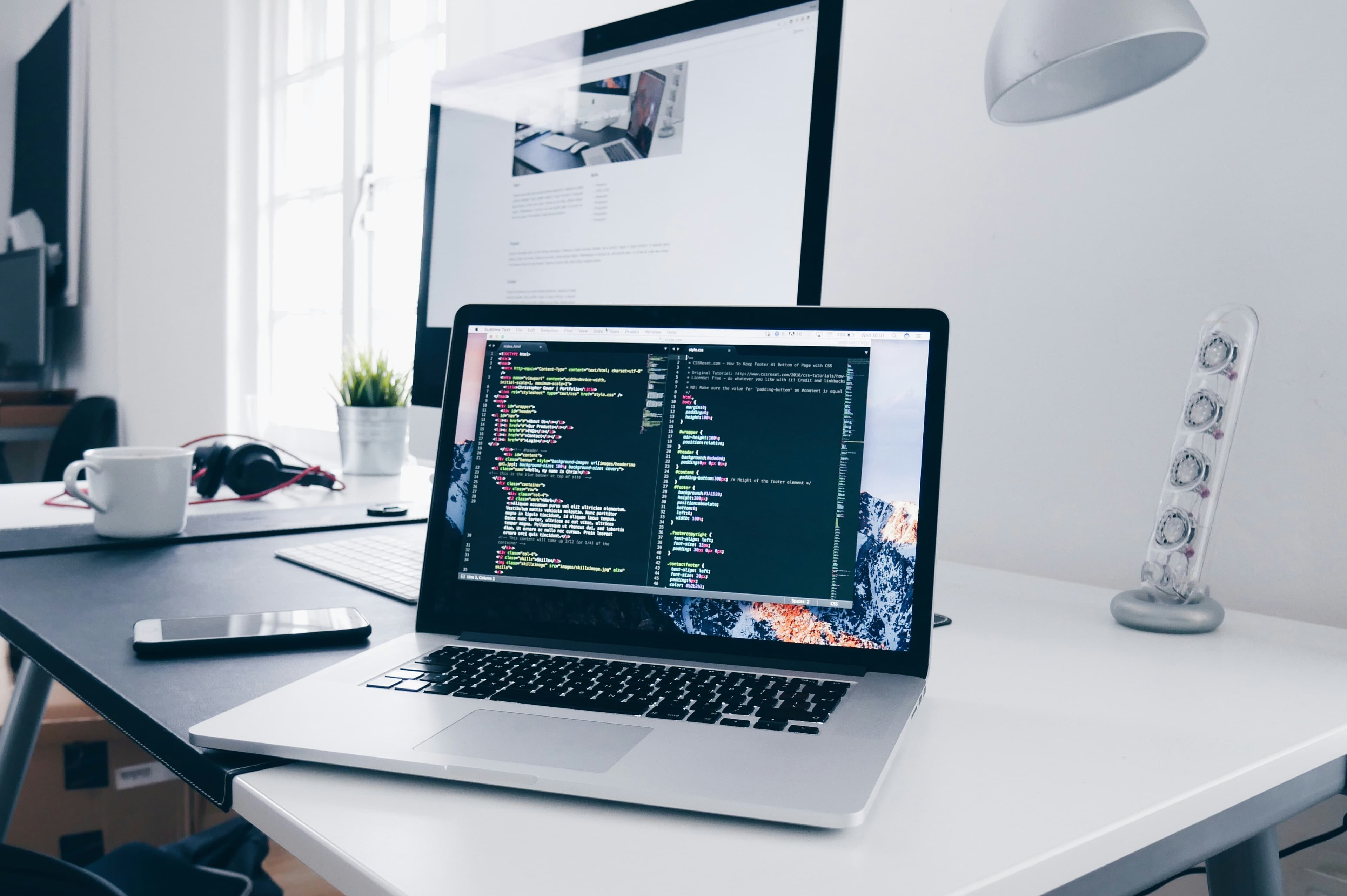 MacBook con líneas de código en su pantalla sobre un escritorio de trabajo