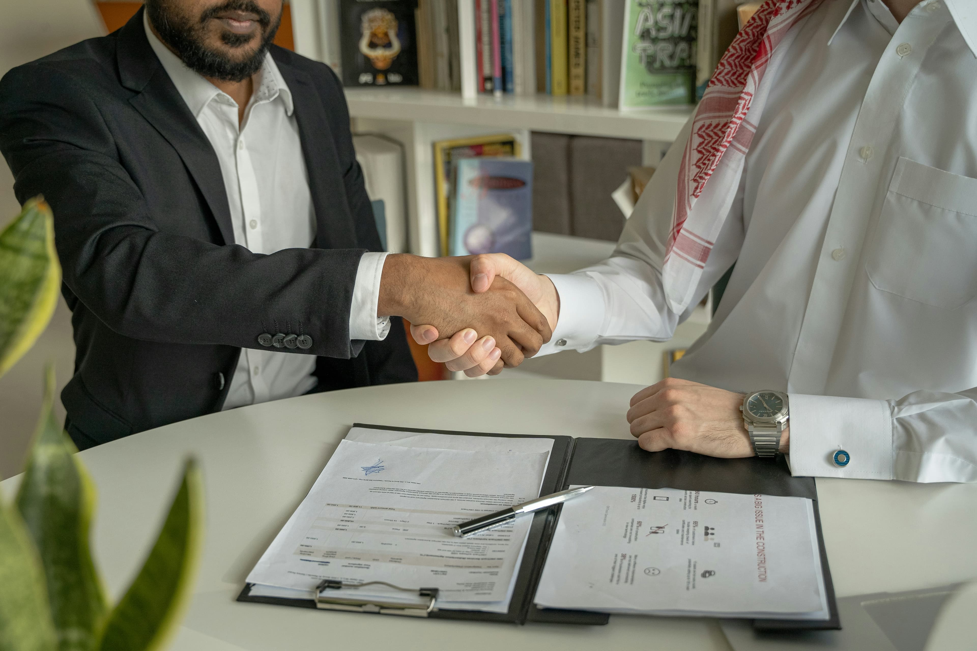 Dos personas dándose la mano sobre un escritorio en señal de bienvenida